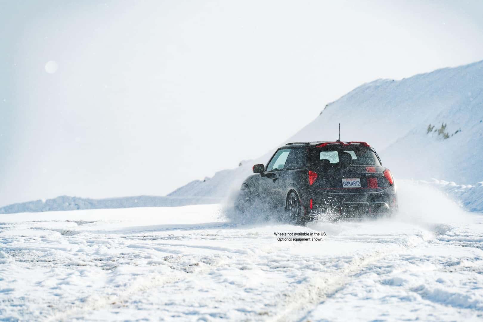 a mini cooper driving in deep snow in the mountains. 