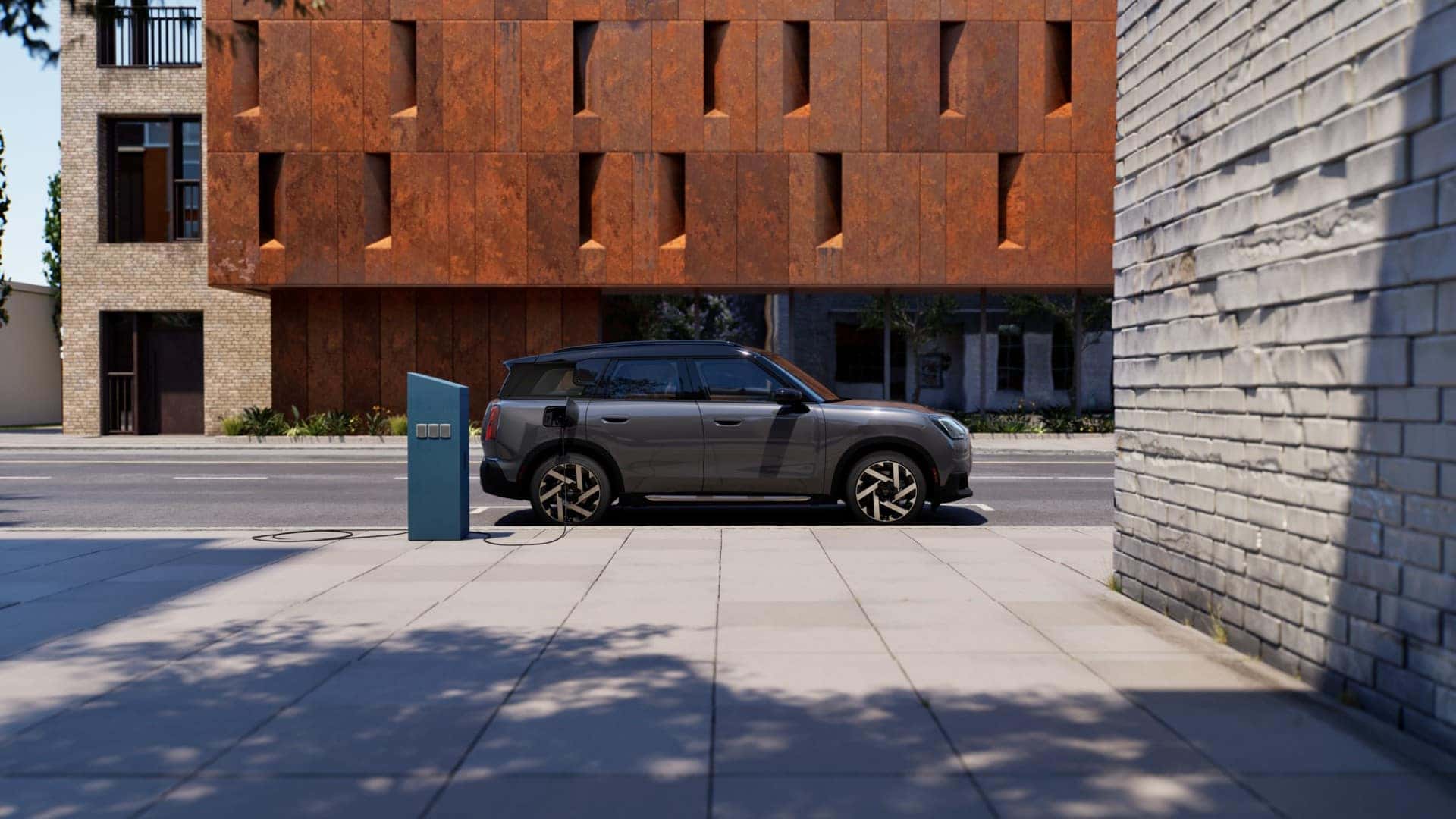 a gray mini cooper parked and charging next to a building