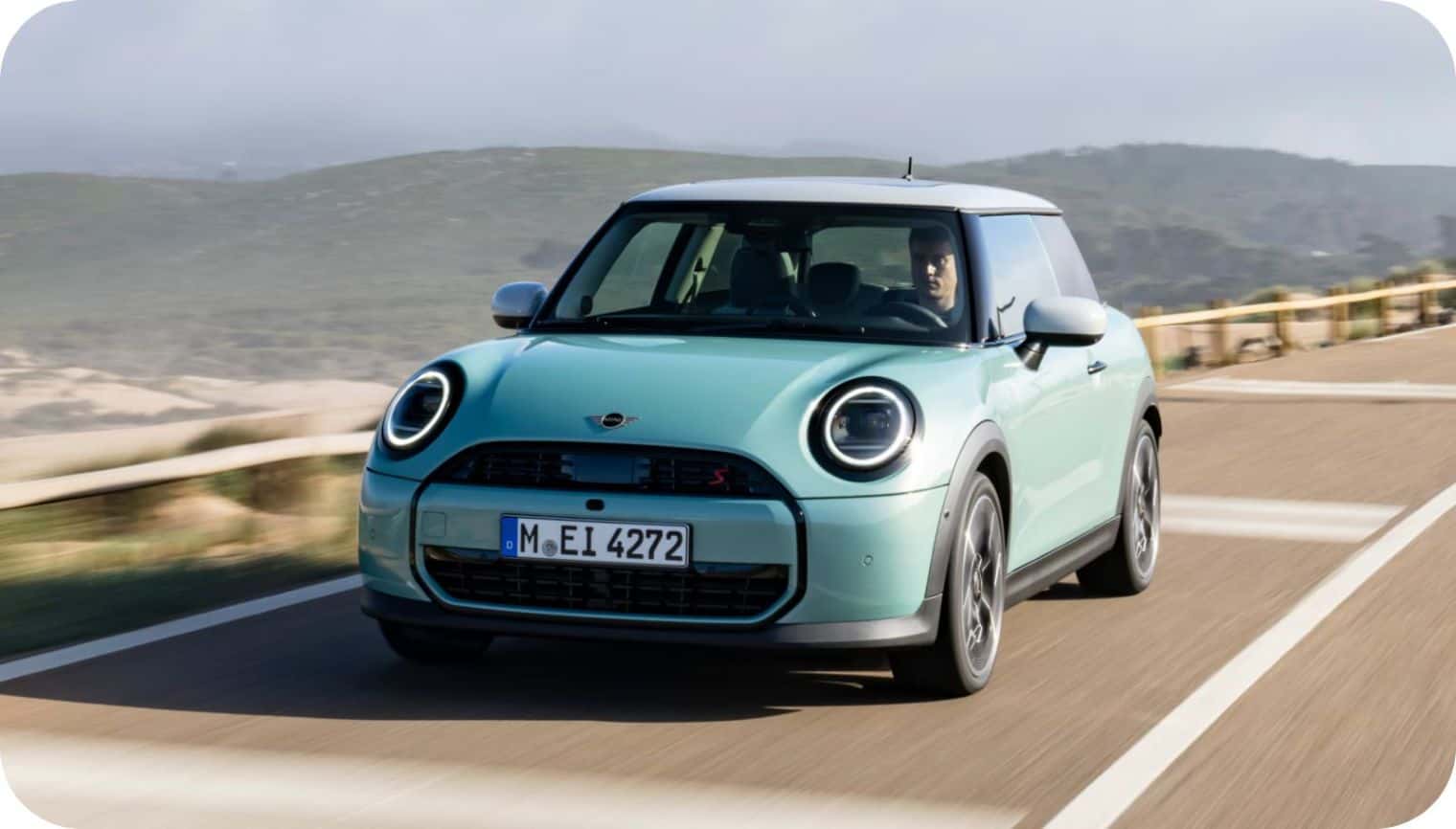 a mini cooper 2 door driving on a highway