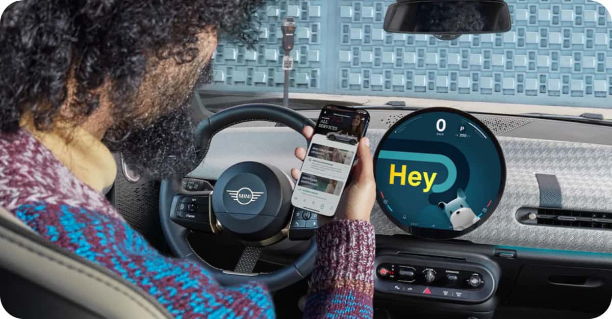 a man looking at the mini app while sitting in the driver's seat of a MINI vehicle