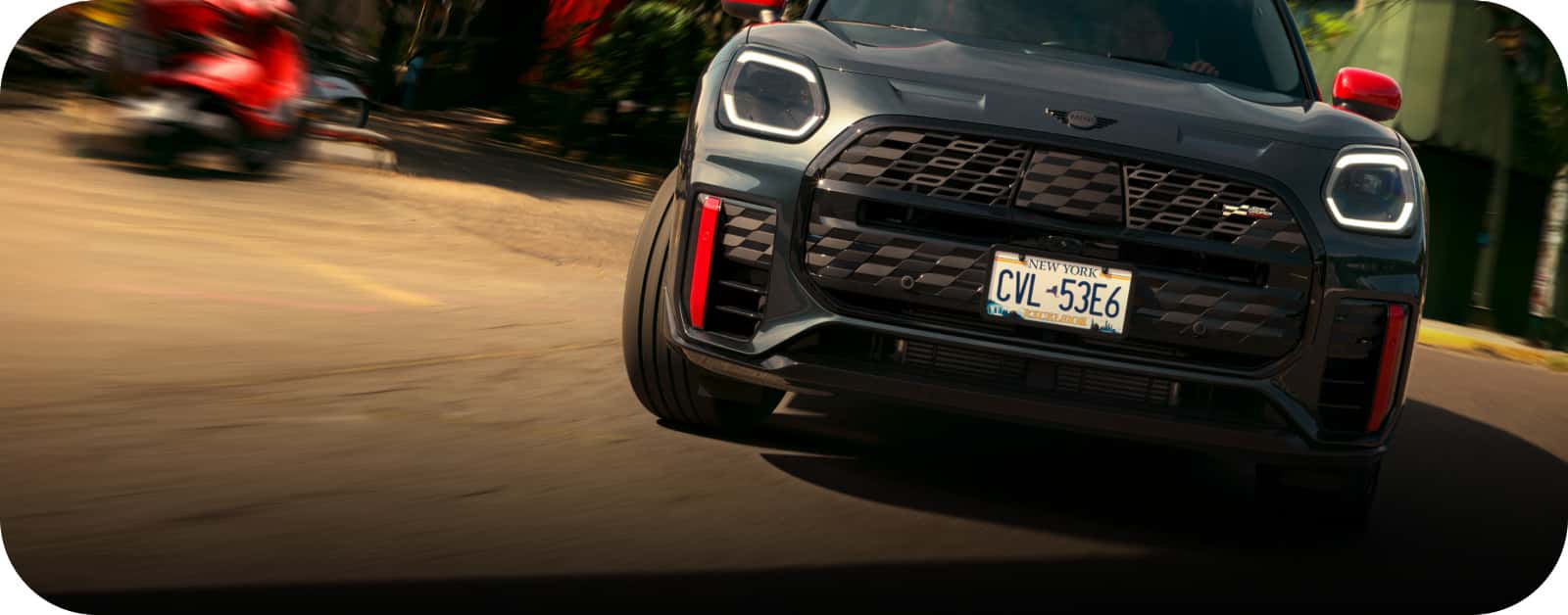 the front of a john cooper works mini cooper 2 door hardtop driving on a dirt road