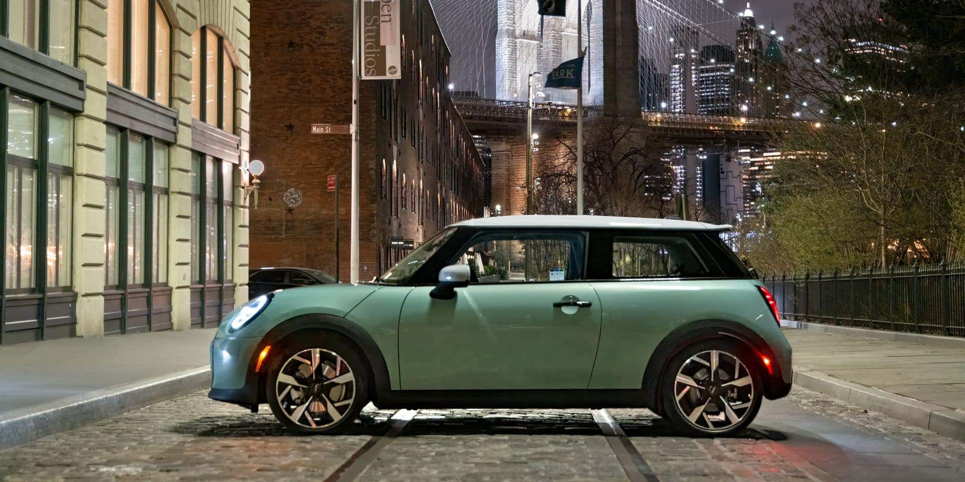 side profile of a 2025 mini cooper 2 door parked in the middle of a road in a city