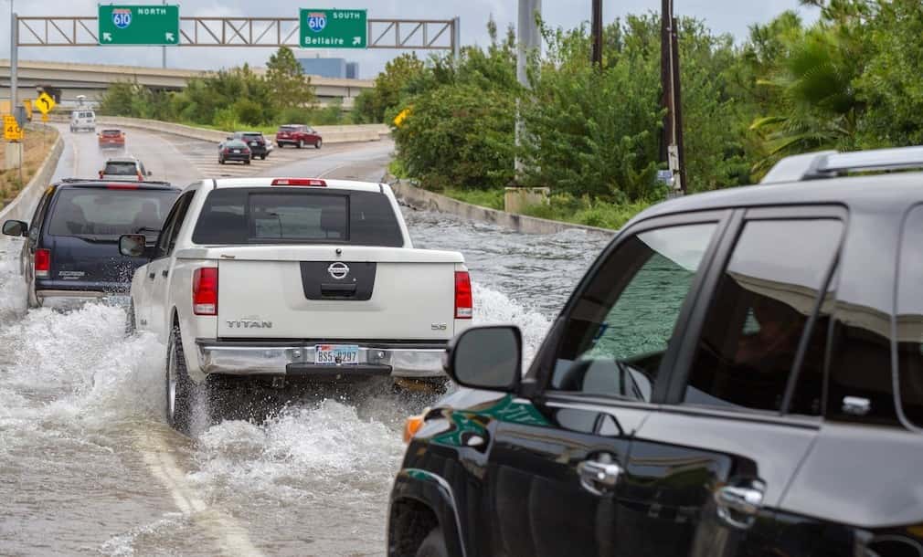 Cars and trucks drive through flooded water