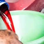 Hand pouring transmission fluid through funnel as for the good car maintenance