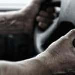 Worker with hands holding steering wheel.