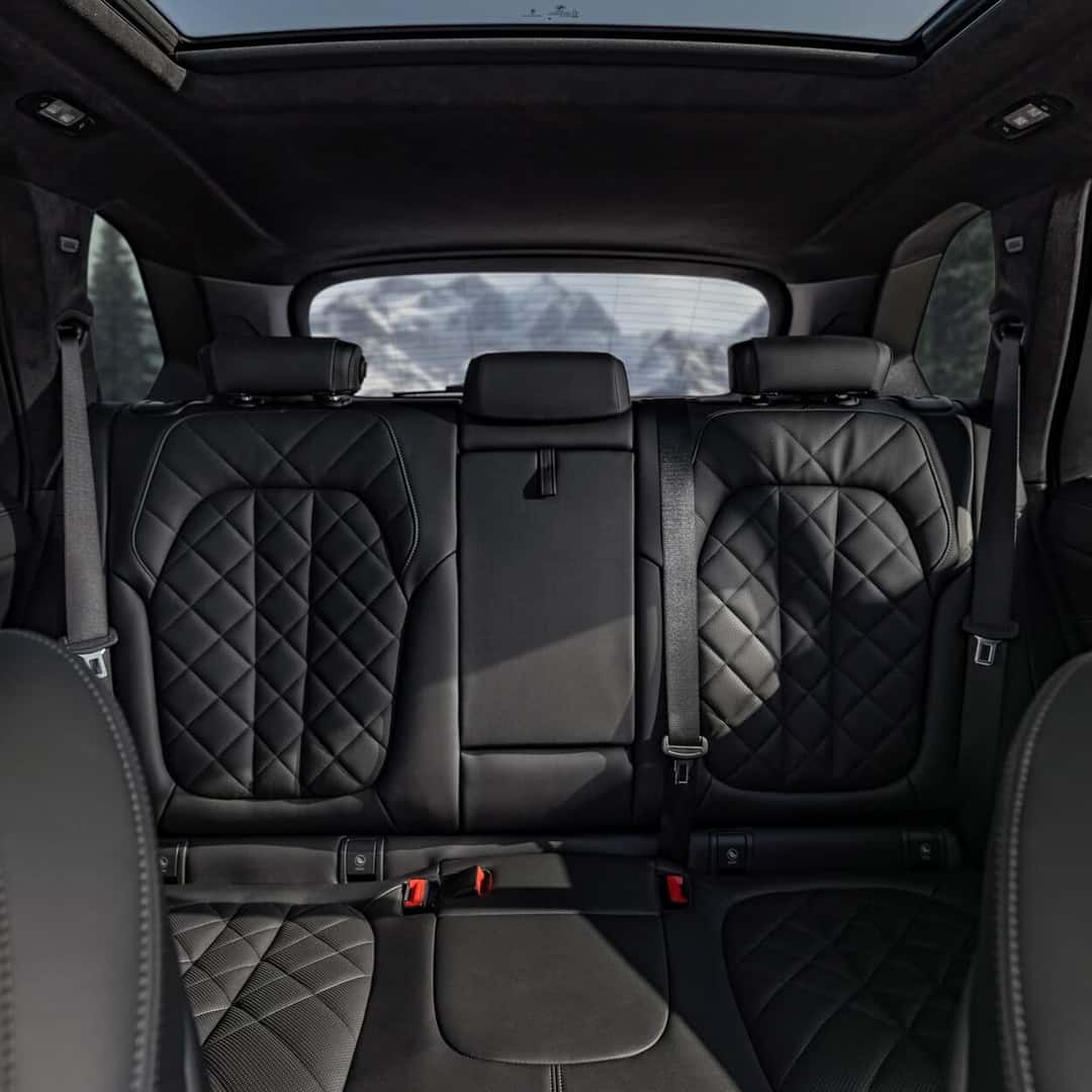 Rear seat view of the 2025 BMW X5 showcasing quilted leather upholstery and panoramic glass roof