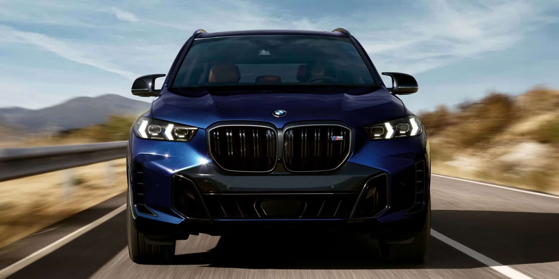 theh front of a blue bmw x5 driving in the desert