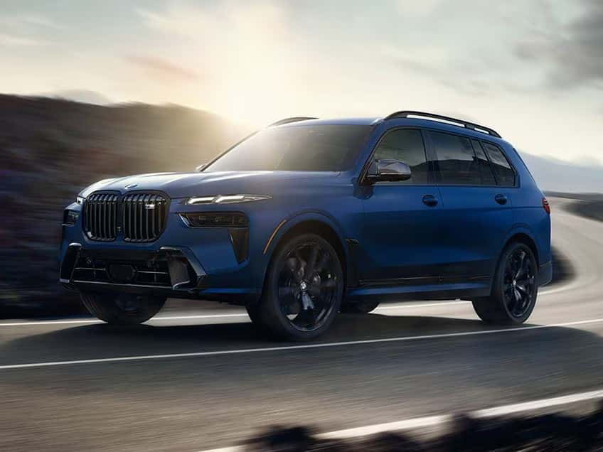 a blue bmw x7 suv driving on a winding road