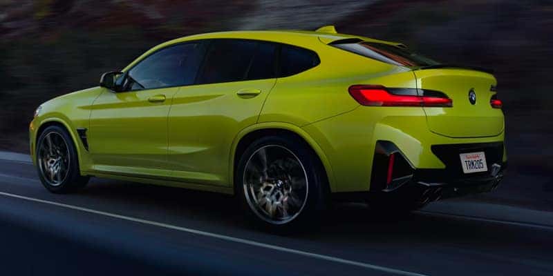 a yellow bmw driving on a highway at night.