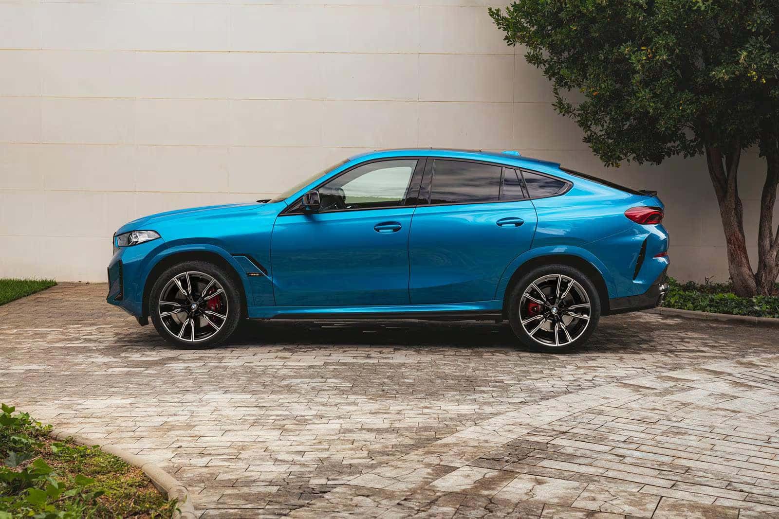 side profile of blue 2026 bmw x6 parked on a brick path
