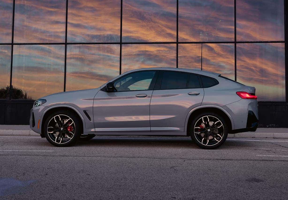 a silver bmw x4 parked next to a building with glass windows