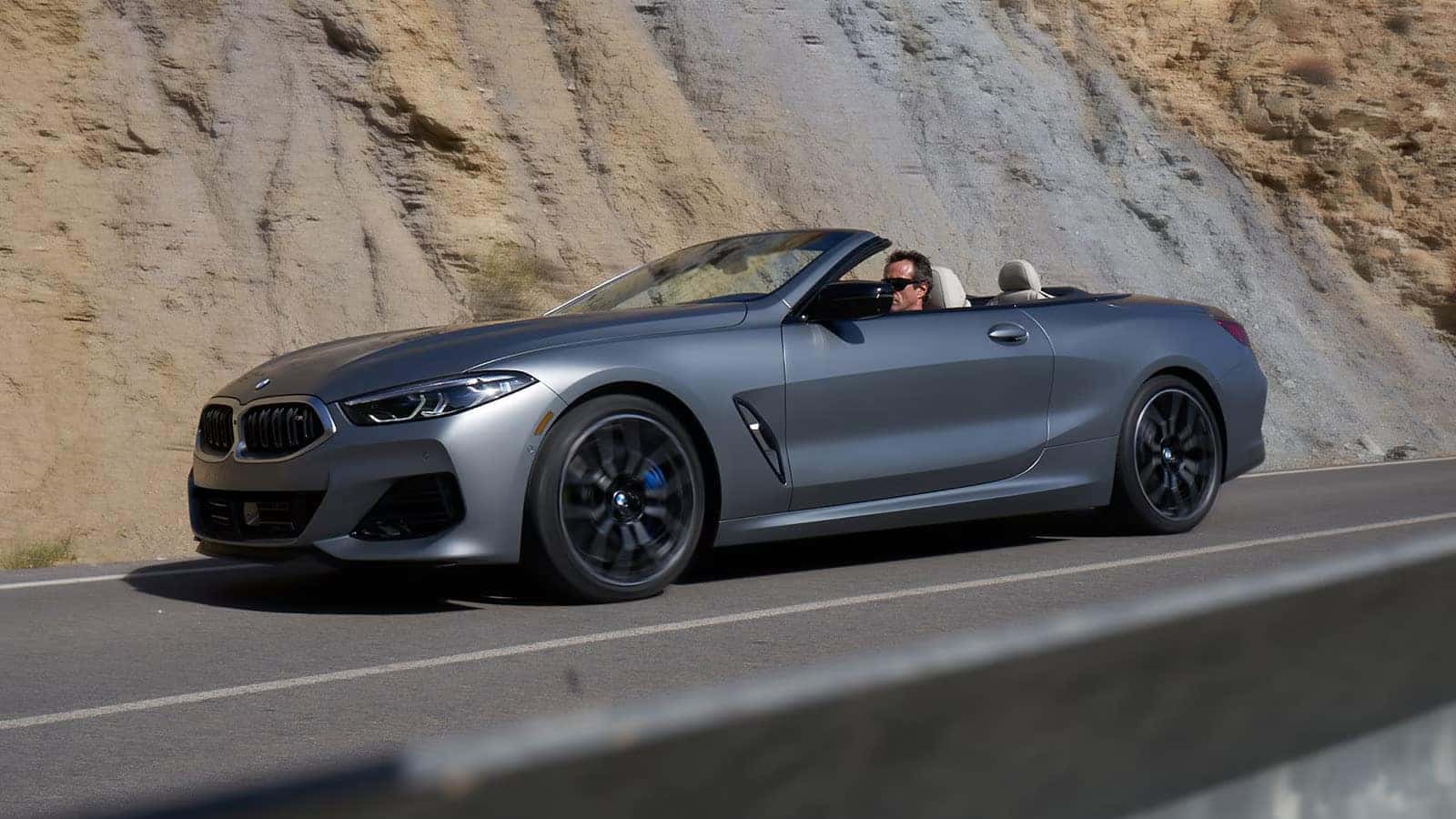 2026 bmw 8 series convertible driving near a mountain wall
