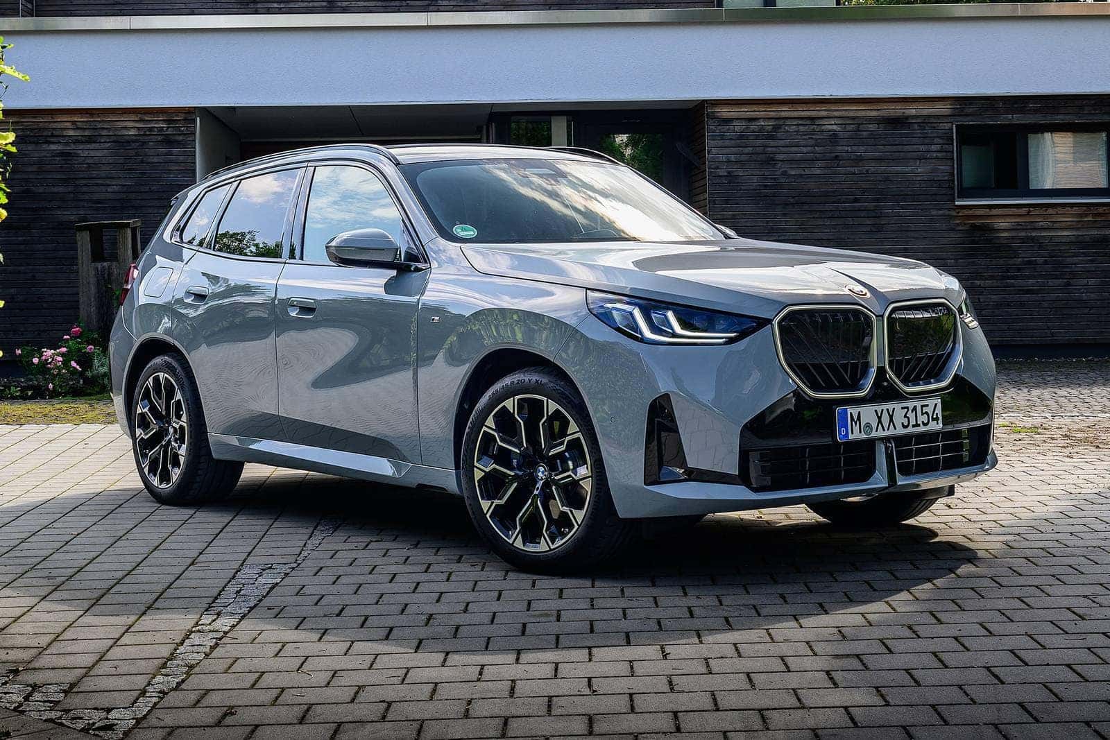 a grey 2026 BMW X3 parked in front of a building