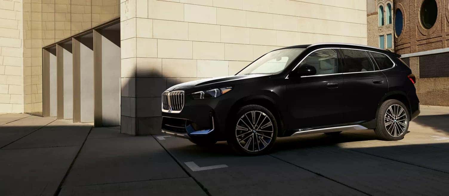 a black BMW X1 parked next to a building