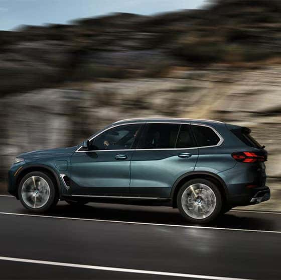 a New 2026 BMW X5 driving down a mountain road
