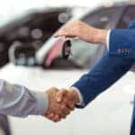 Handshake of two businessmen when selling a car in a motor show, close-up