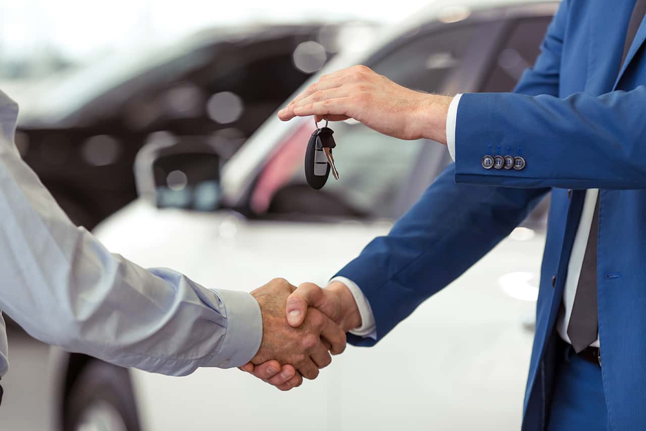 Handshake of two businessmen when selling a car in a motor show, close-up