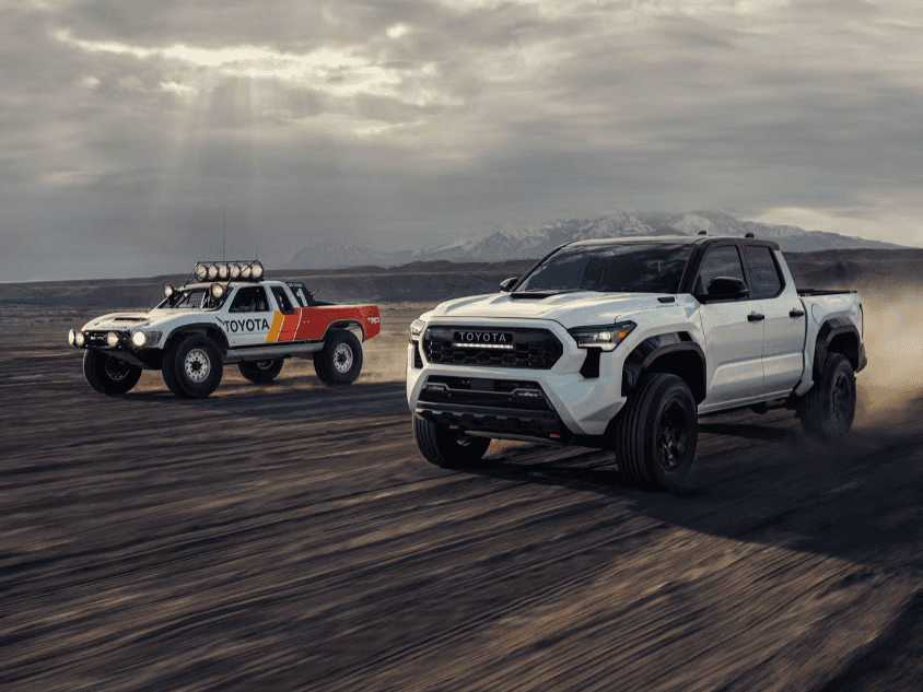 2026 Toyota Tacoma racing a vintage Toyota truck in the desert