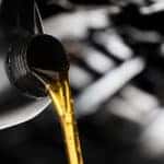Pouring oil lubricant motor car from black bottle on engine background oil change auto shop