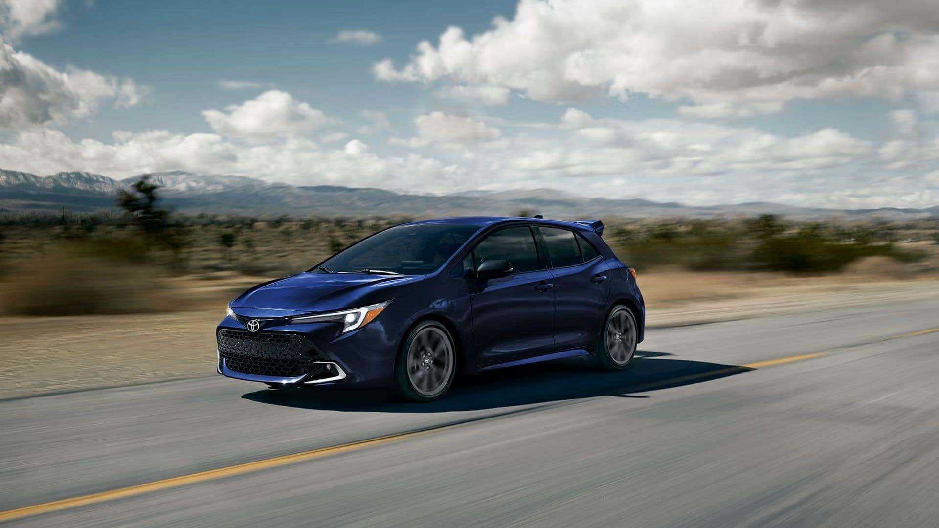 Blue 2027 Toyota Corolla Hatchback driving down desert road