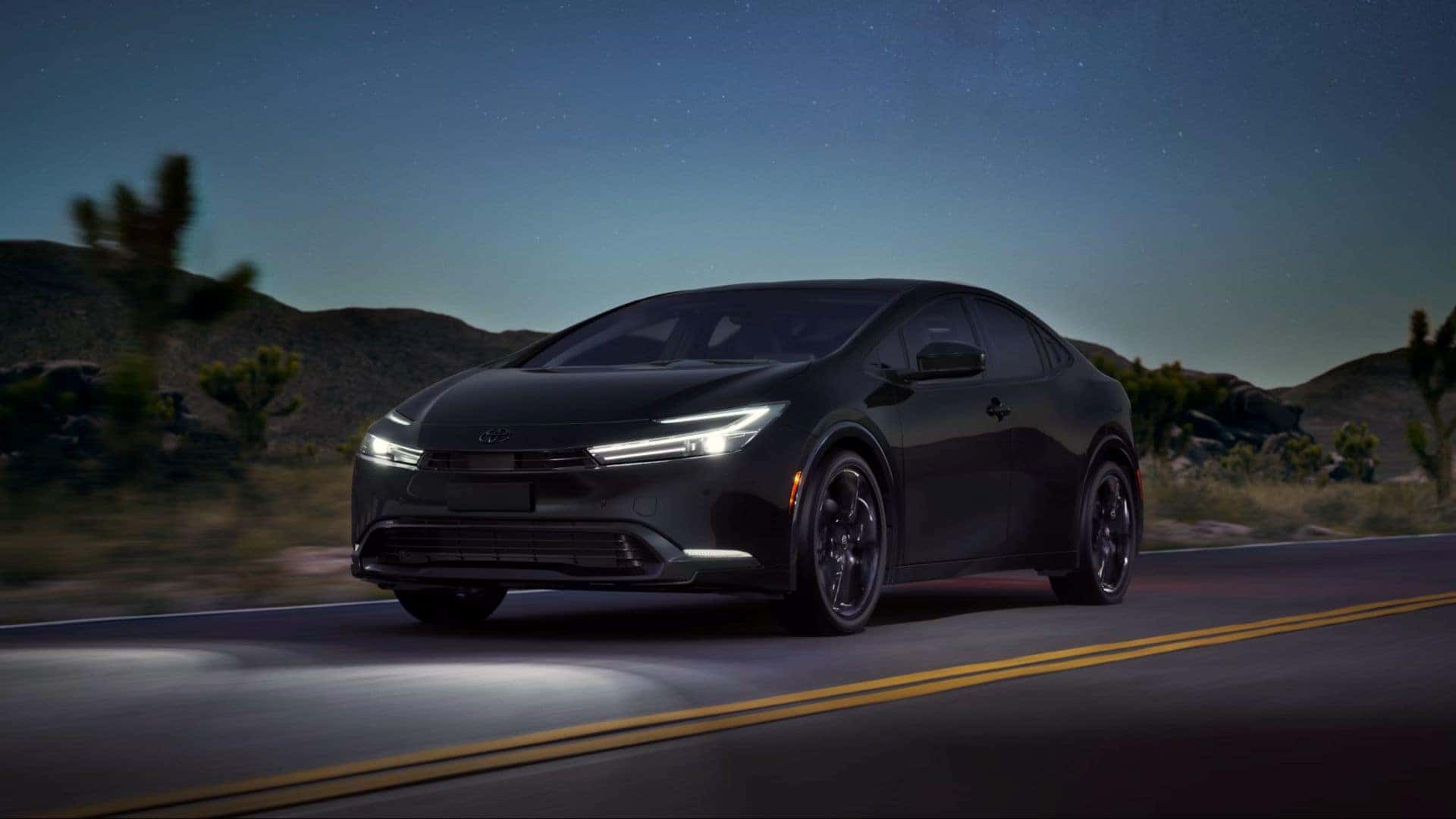 Black 2027 Toyota Prius Plug-In Hybrid Driving down desert road at nighttime
