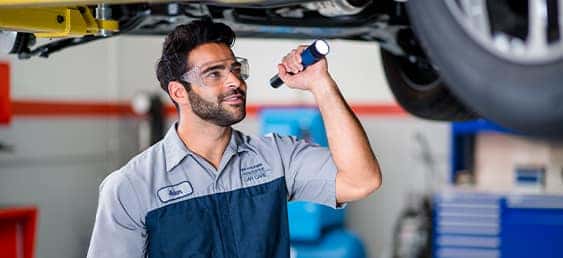 How to check your tires' health at Washington Hyundai of Washington | Mechanic checking under car with flashlight