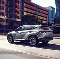 Hyundai Hybrid for Everyone at Washington Hyundai | Rear of Tucson driving fast on city street