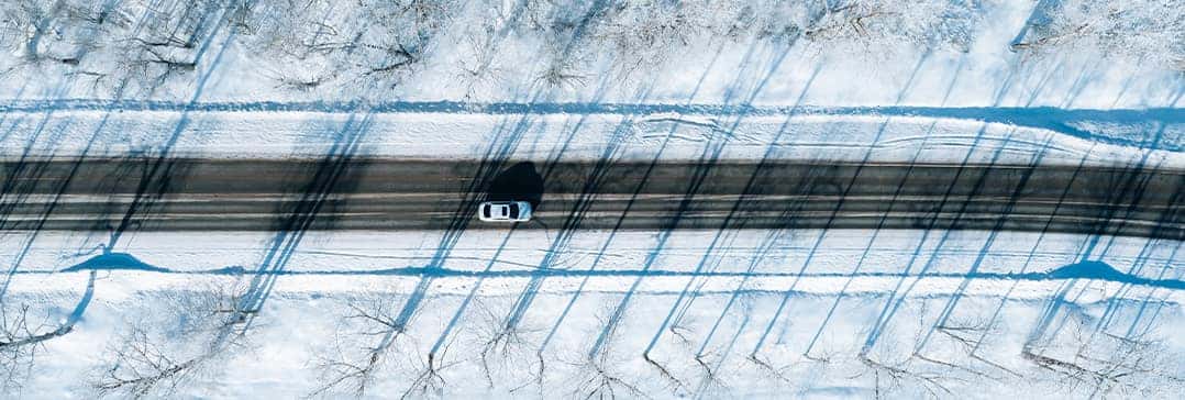 How to prepare your Hyundai for the winter season in Washington, PA at Washington Hyundai | Bird's-eye view of car driving on snowy back road in forest