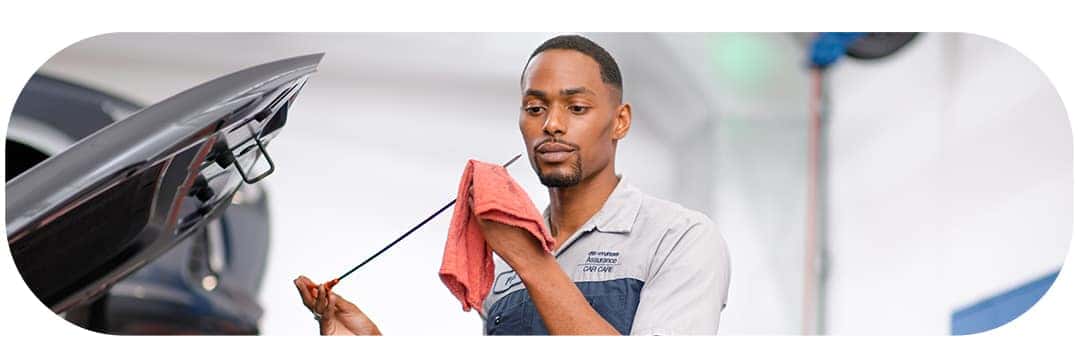 Difference between synthetic oil & conventional oil at Washington Hyundai | Close-up of Hyundai Technician uses dipstick to check oil from car's engine bay